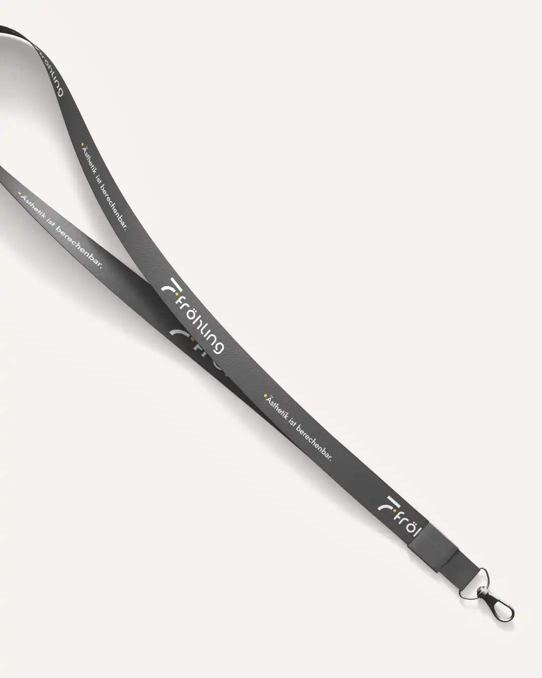 Schlüsselband (Lanyard) im Corporate Design der Fröhling Ingenieure GmbH in dunklem Anthrazit, bedruckt mit Logo und dem Slogan „Ästhetik ist berechenbar.", mit schwarzer Kunststoffklemme und Metallkarabiner.