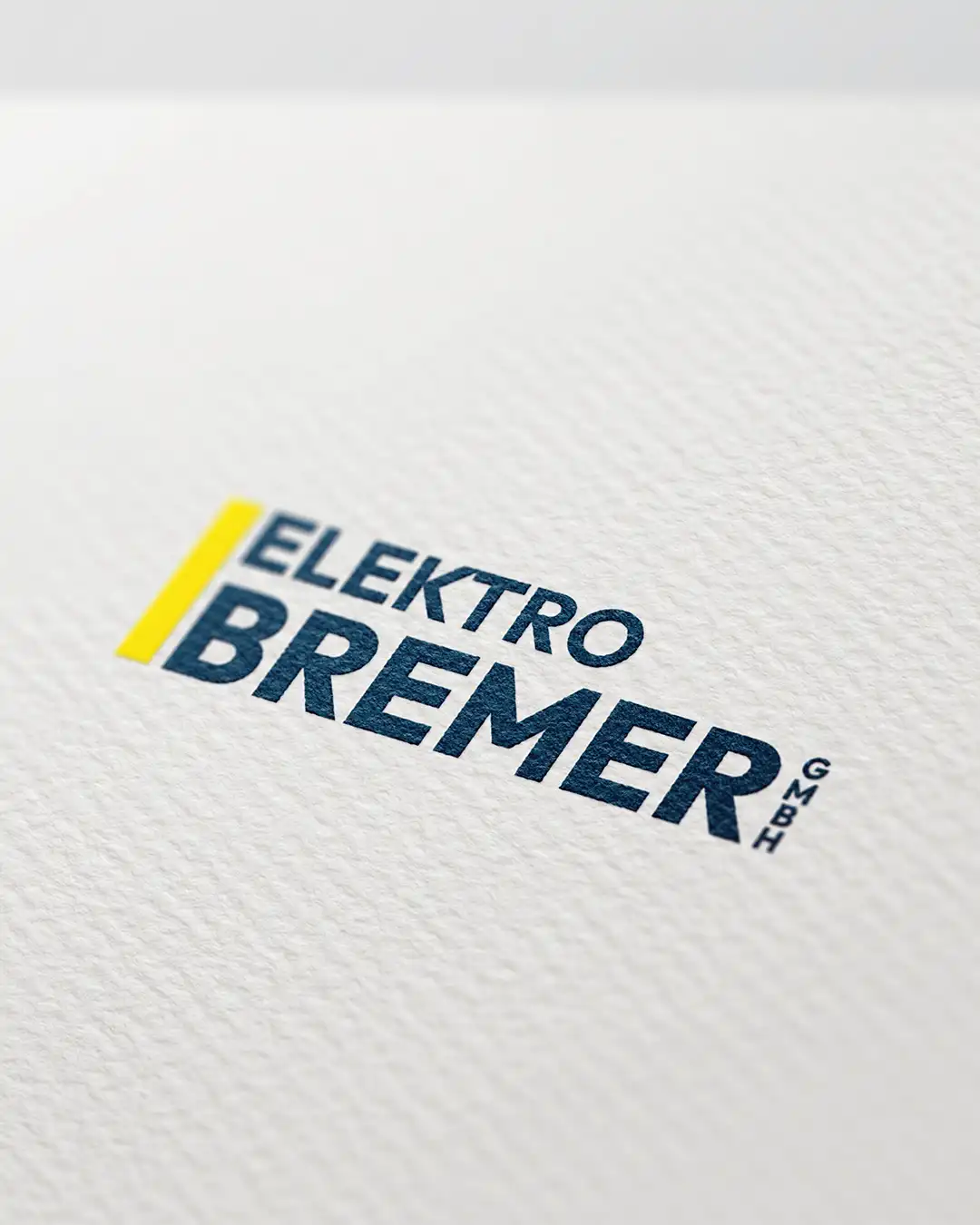 Logo der Elektro Bremer GmbH in Dunkelblau und Gelb auf strukturiertem Papier